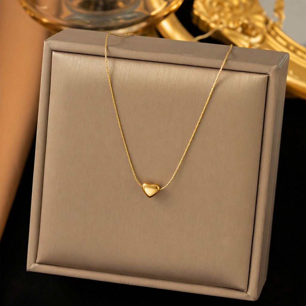 A gold-plated stainless steel chain for women featuring a tiny, puffed heart pendant on a delicate link chain didplayed on a showcase