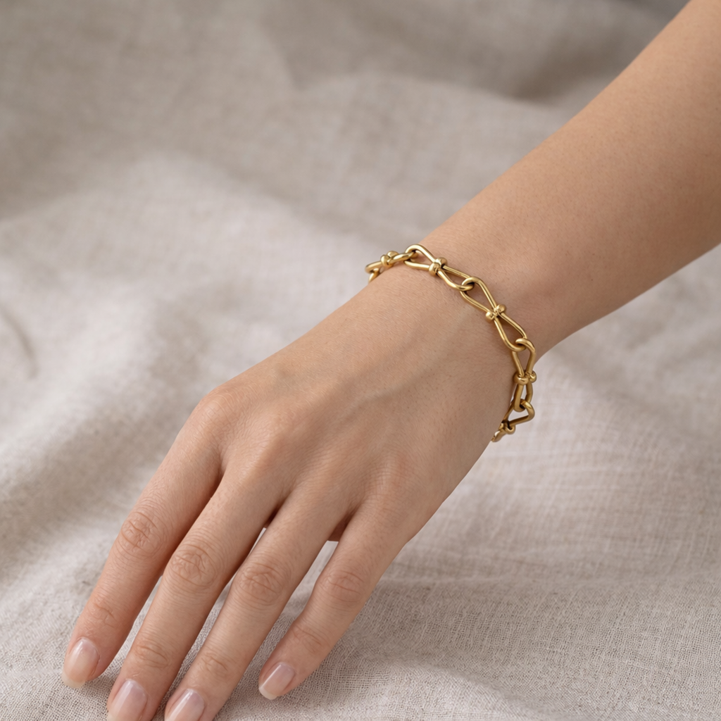 A gold-plated link chain bracelet for women featuring delicate knot details on a model hand