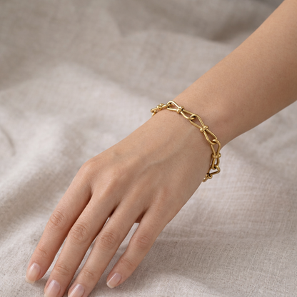 A gold-plated link chain bracelet for women featuring delicate knot details on a model hand