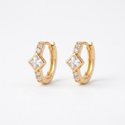 A pair of gold-plated huggie hoop earrings for women featuring a central kite-set princess-cut clear crystal, shown on a clean white background.
