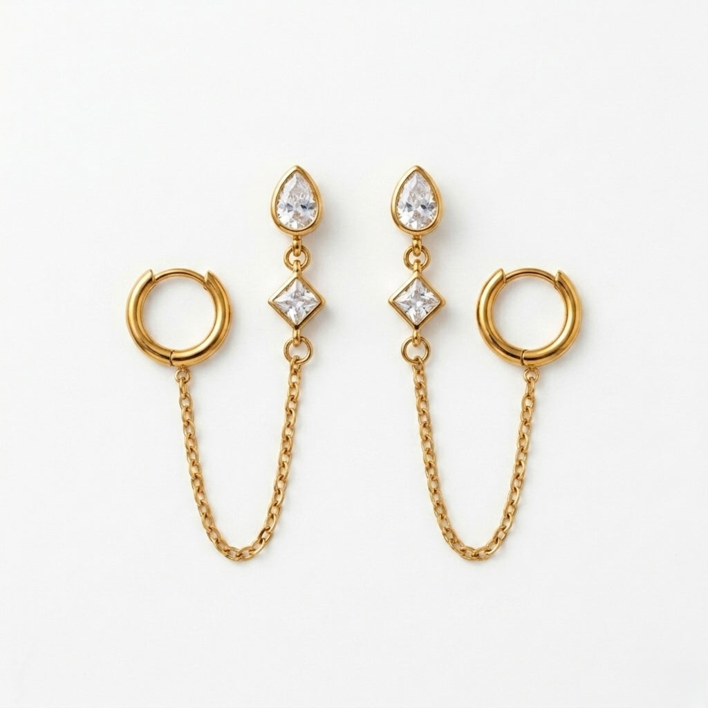 A pair of gold-plated ear chain earrings for women connecting a tiered crystal drop stud to a small gold hoop with a fine chain.