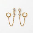 A pair of gold-plated ear chain earrings for women connecting a tiered crystal drop stud to a small gold hoop with a fine chain.