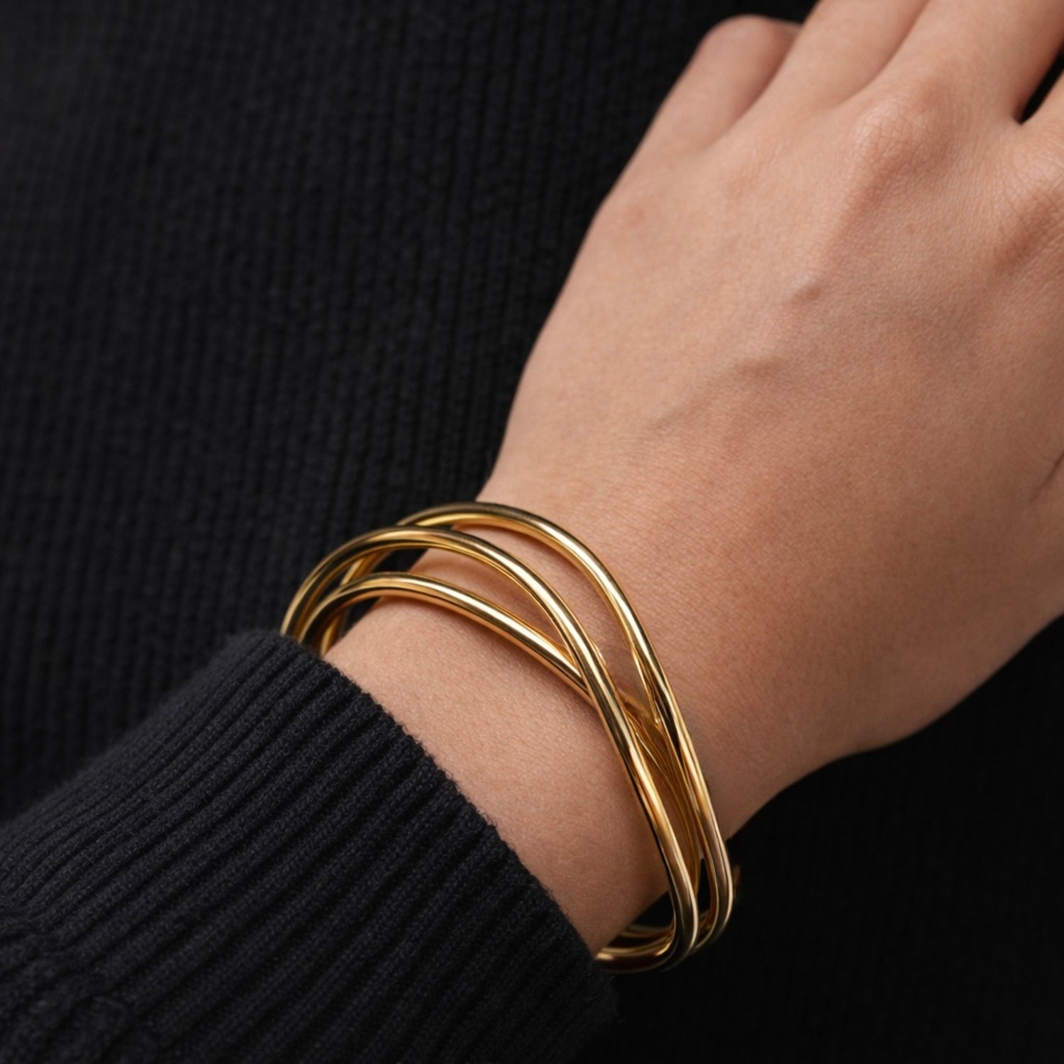 A bold and modern gold-plated triple-band adjustable cuff bracelet for women featuring an organic wave design, displayed on a model hand