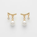 A pair of gold-plated arc drop earrings for women featuring a central white pearl and a small clear crystal, shown on a white background.