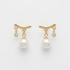 A pair of gold-plated arc drop earrings for women featuring a central white pearl and a small clear crystal, shown on a white background.