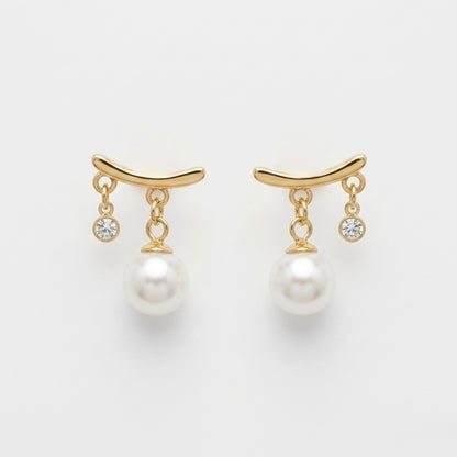 A pair of gold-plated arc drop earrings for women featuring a central white pearl and a small clear crystal, shown on a white background.