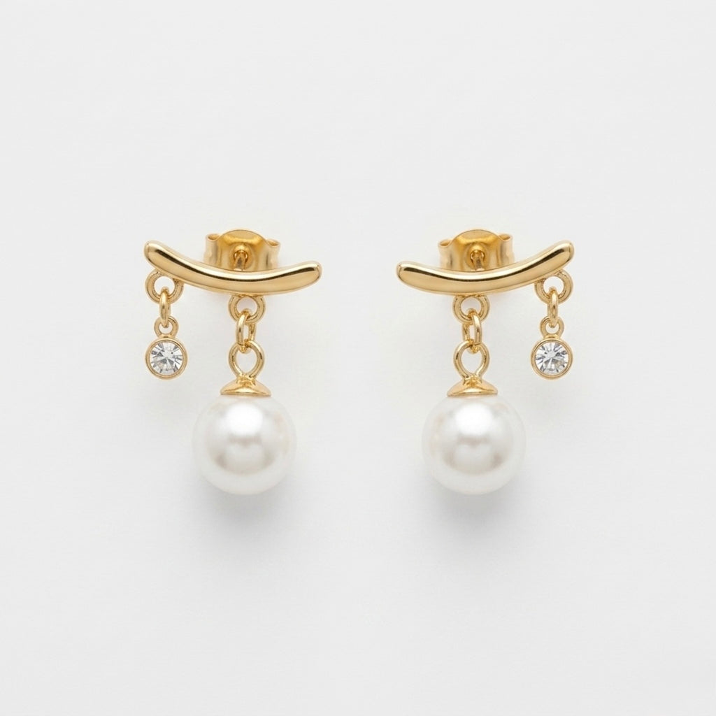 A close-view of a pair of gold-plated arc drop earrings for women featuring a central white pearl and a small clear crystal, shown on a white background