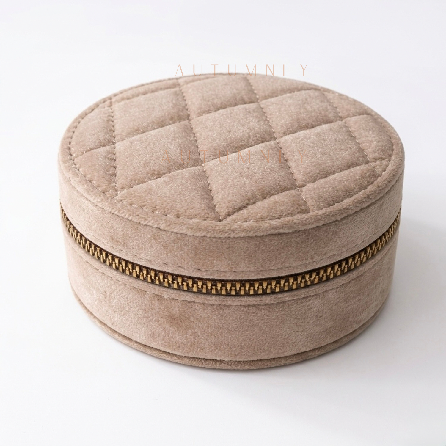 Beige round quilted jewelry box with a gold zipper on a white background