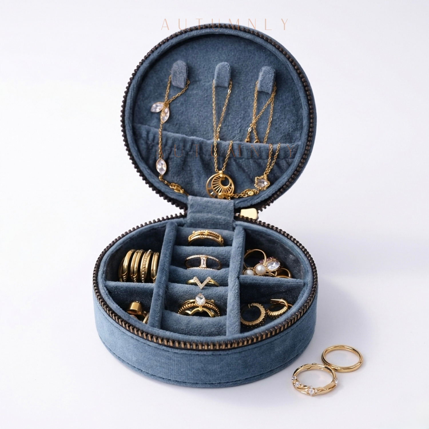 tealblue jewelry organizer with gold jewelry arranged across multiple compartments on a white background