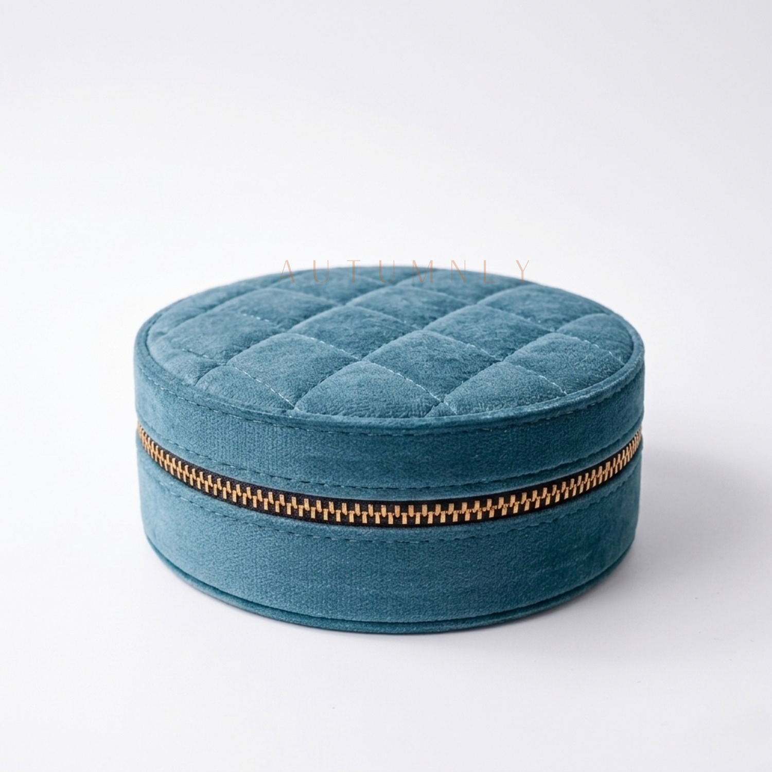 Teal blue round quilted jewelry box with a gold zipper on a white background