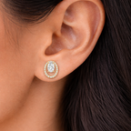 A gold-plated oval stud earrings for women featuring a floating central clear crystal surrounded by a pavé halo, shown on a model