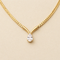 A close-view of a gold-plated stainless steel chain for women featuring a V-shaped mounting and a large sparkling teardrop crystal pendant