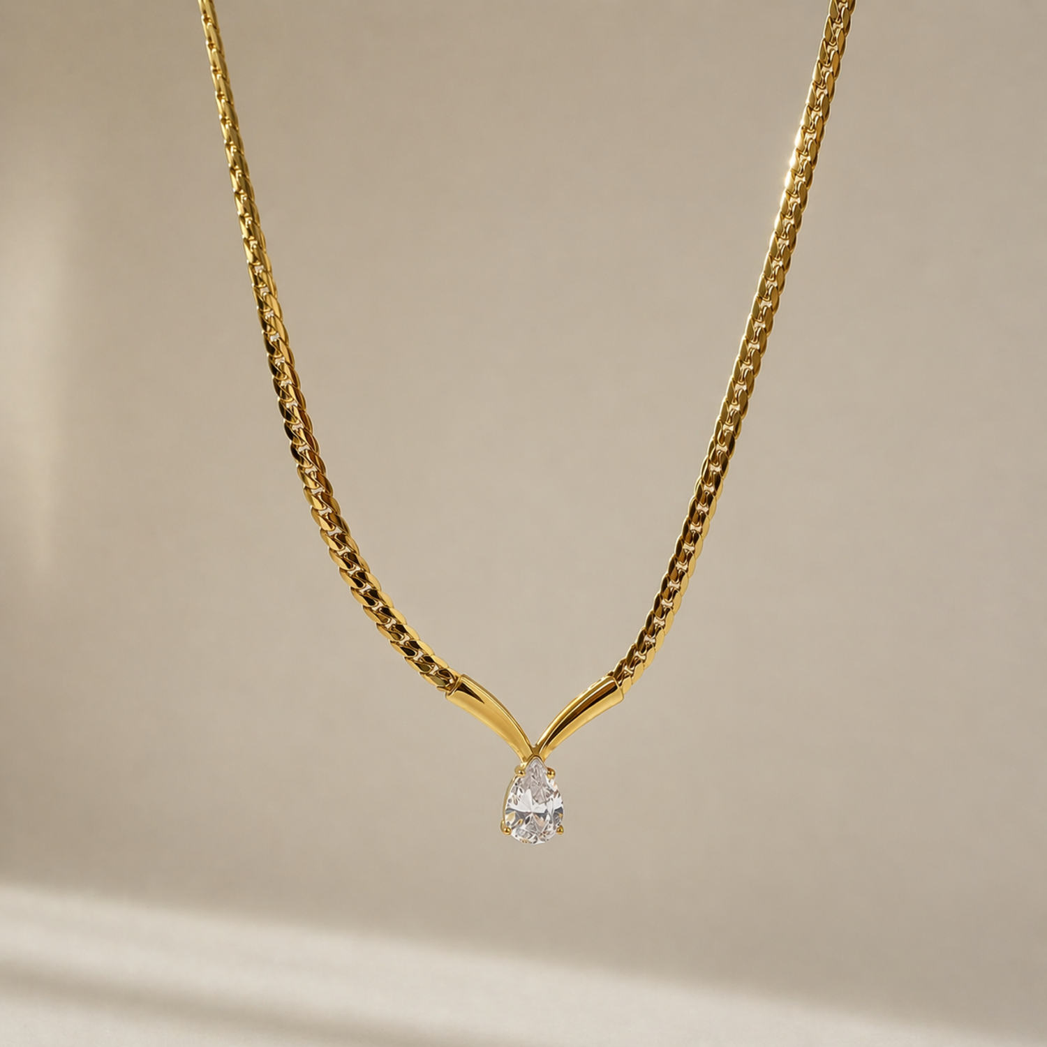 A gold-plated stainless steel chain for women featuring a V-shaped mounting and a large sparkling teardrop crystal pendant