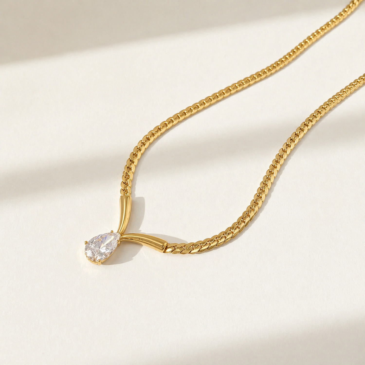 A gold-plated stainless steel chain for women featuring a V-shaped mounting and a large sparkling teardrop crystal pendant