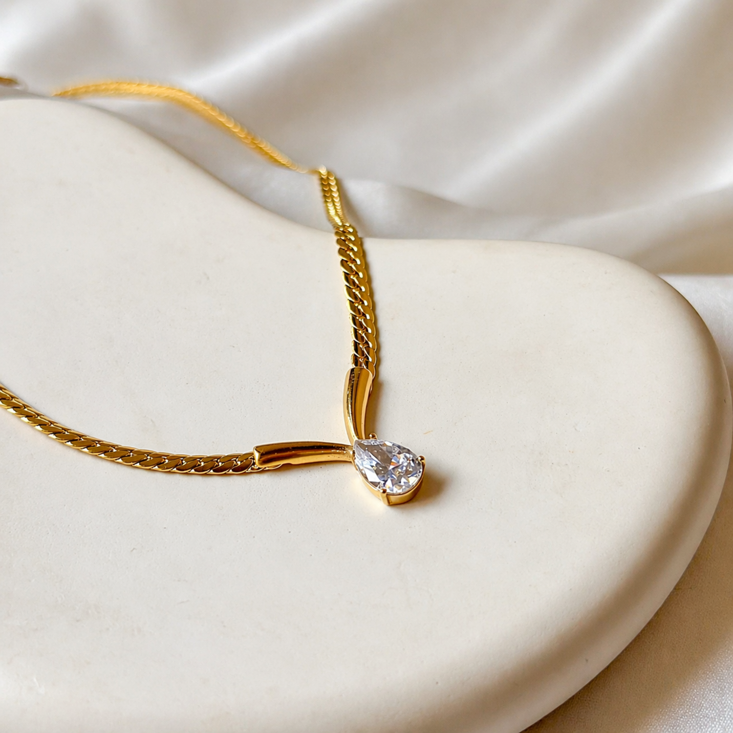 A gold-plated stainless steel chain for women featuring a V-shaped mounting and a large sparkling teardrop crystal pendant