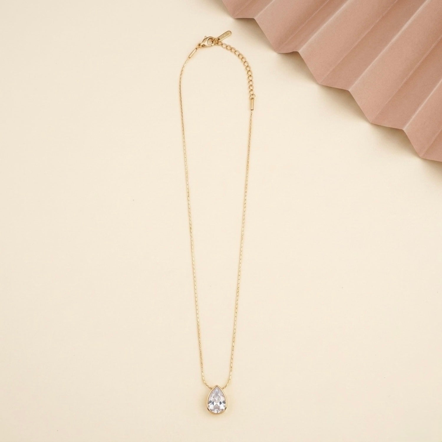 A gold-plated stainless steel chain for women featuring a single, brilliant pear-cut crystal pendant on a delicate link chain.