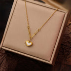 A gold-plated stainless steel chain for women featuring a heart-shaped pendant with a pearl inlay, suspended from elongated paperclip links and a delicate chain displayed on a showcase