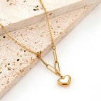 A gold-plated stainless steel chain for women featuring a heart-shaped pendant with a pearl inlay, suspended from elongated paperclip links and a delicate chain.