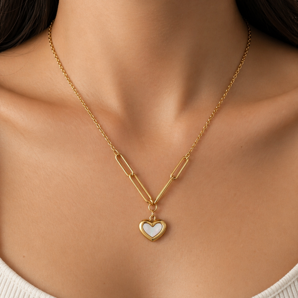 A gold-plated stainless steel chain for women featuring a heart-shaped pendant with a pearl inlay, suspended from elongated paperclip links and a delicate chain, shown on a model