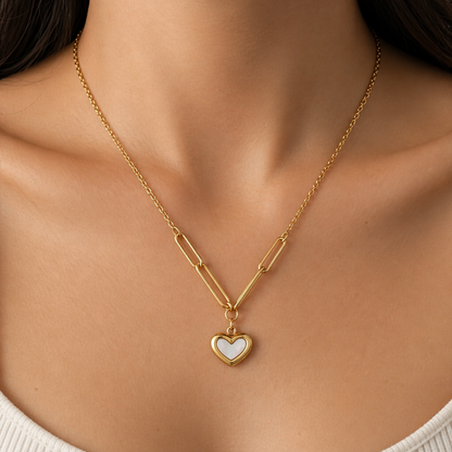 A gold-plated stainless steel chain for women featuring a heart-shaped pendant with a pearl inlay, suspended from elongated paperclip links and a delicate chain, shown on a model
