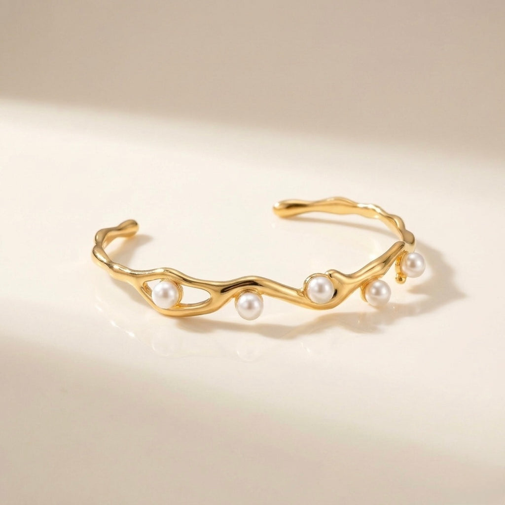 A gold-plated wave cuff bangle for women featuring five set pearls