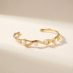 A gold-plated wave cuff bangle for women featuring five set pearls