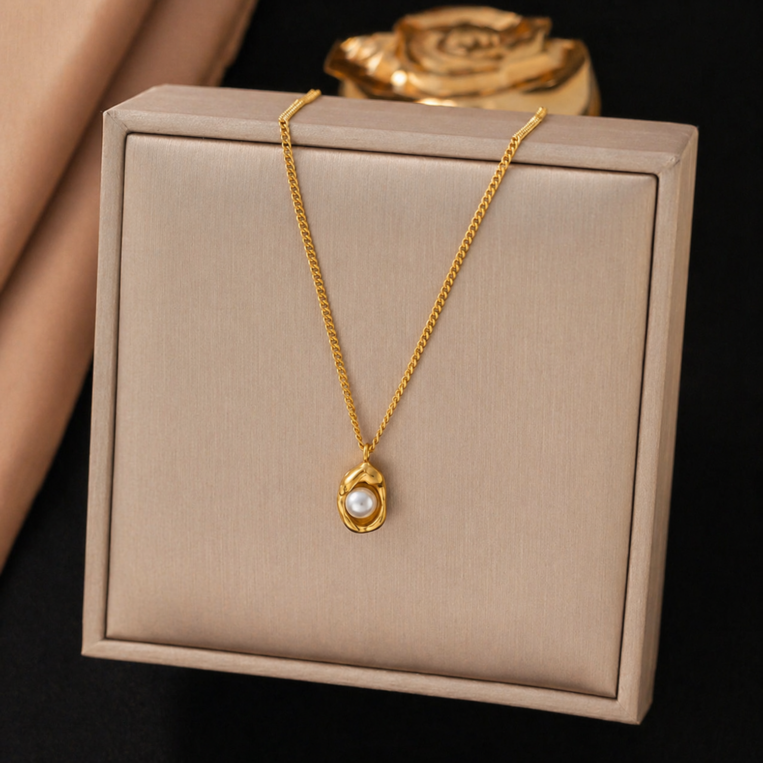 A close-view of a gold-plated stainless steel chain for women featuring an organic, molten-gold pendant set with a single white pearl