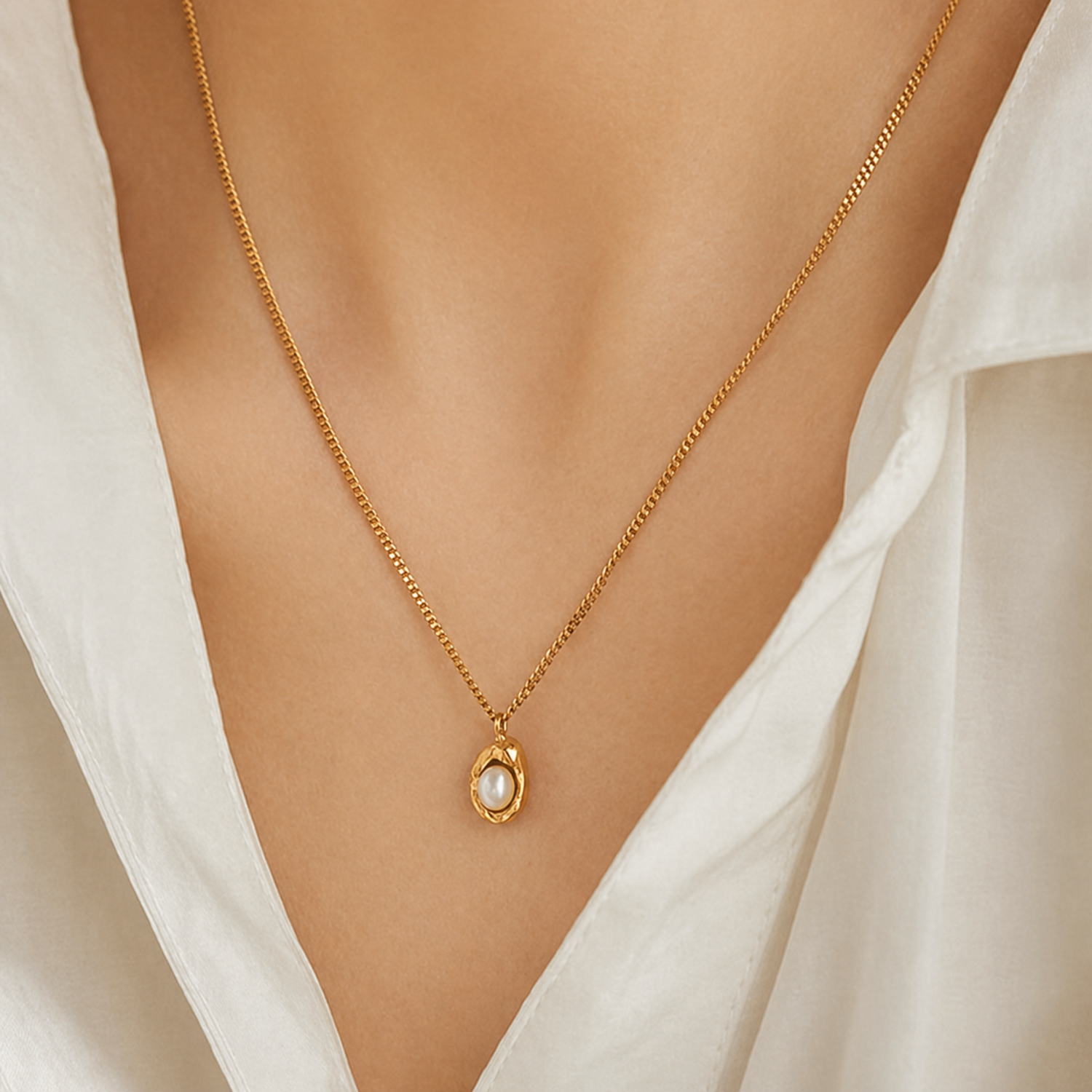 A gold-plated stainless steel chain for women featuring an organic, molten-gold pendant set with a single white pearl, shown on a model