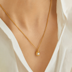 A gold-plated stainless steel chain for women featuring an organic, molten-gold pendant set with a single white pearl, on a model