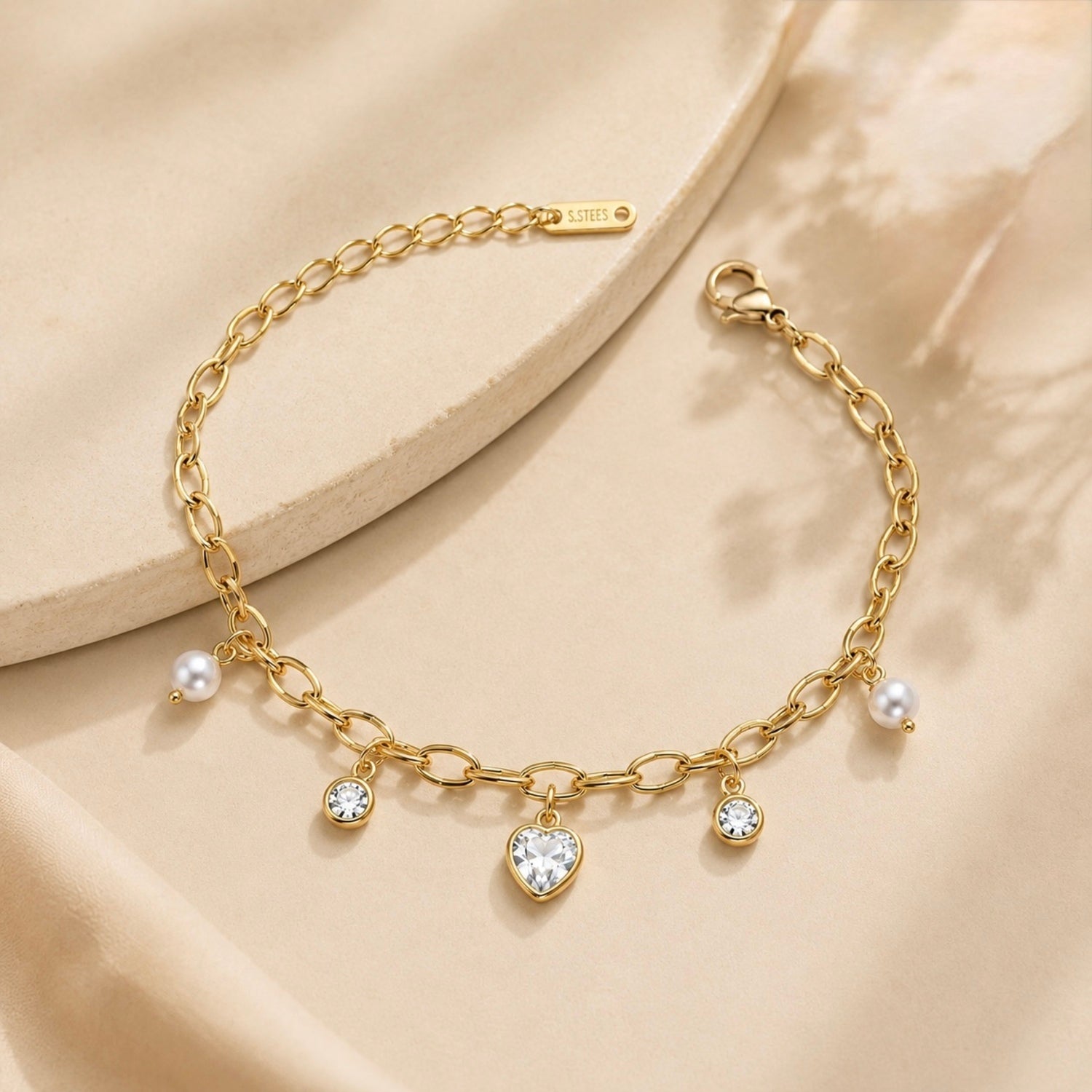 A gold-plated chain bracelet for women featuring dangling pearl charms, round crystals, and a central heart-shaped crystal pendant.