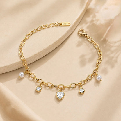 A gold-plated chain bracelet for women featuring dangling pearl charms, round crystals, and a central heart-shaped crystal pendant.
