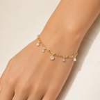 A gold-plated chain bracelet for women featuring dangling pearl charms, round crystals, and a central heart-shaped crystal pendant, shown on a model