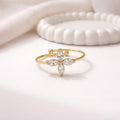 A delicate gold plated adjustable ring for women featuring a four-petal flower design on a white surface.