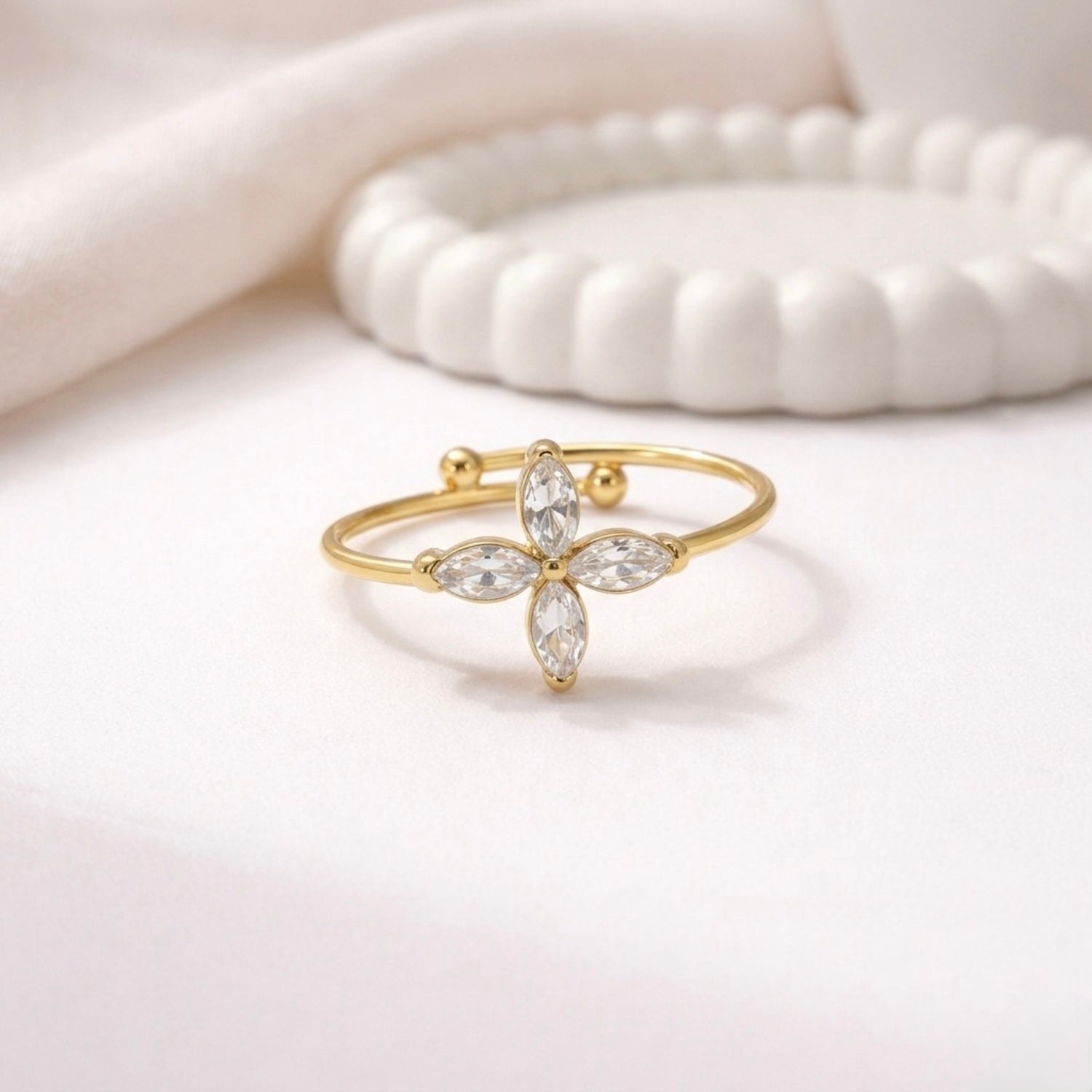 A delicate gold plated adjustable ring for women featuring a four-petal flower design on a white surface.