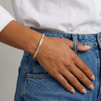 A gold-plated bracelet for women featuring a row of channel-set square-cut crystals and a secure side-clasp, shown on a model