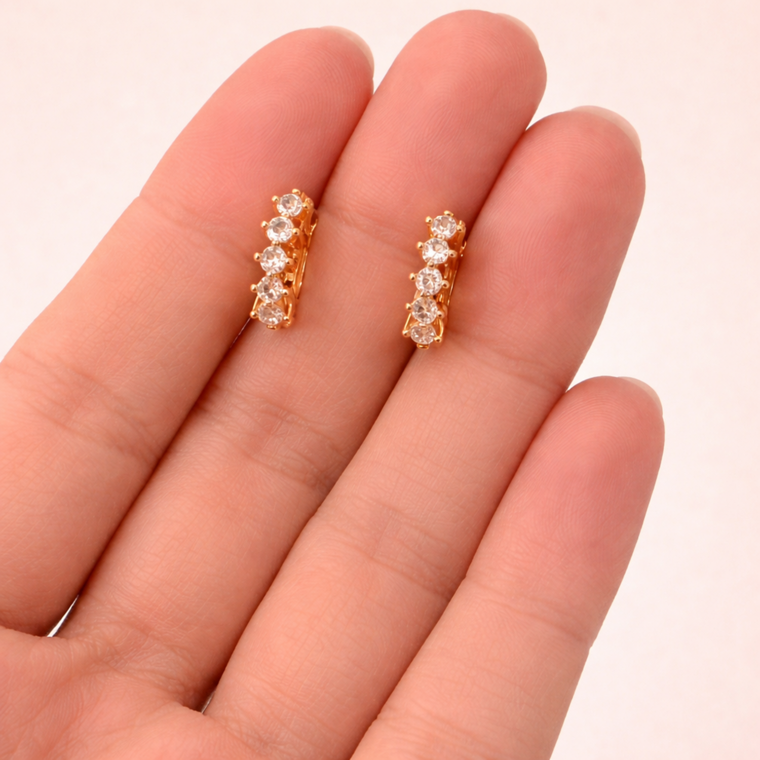 A pair of gold-plated hoop earrings for women featuring a row of five brilliant clear crystals