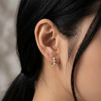 A gold-plated hoop earrings for women featuring a row of five brilliant clear crystals, shown on a model