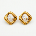A pair of gold-plated abstract rhombus-shaped stud earrings for women featuring two floating crystals inside a molten gold frame, shown on a white background.