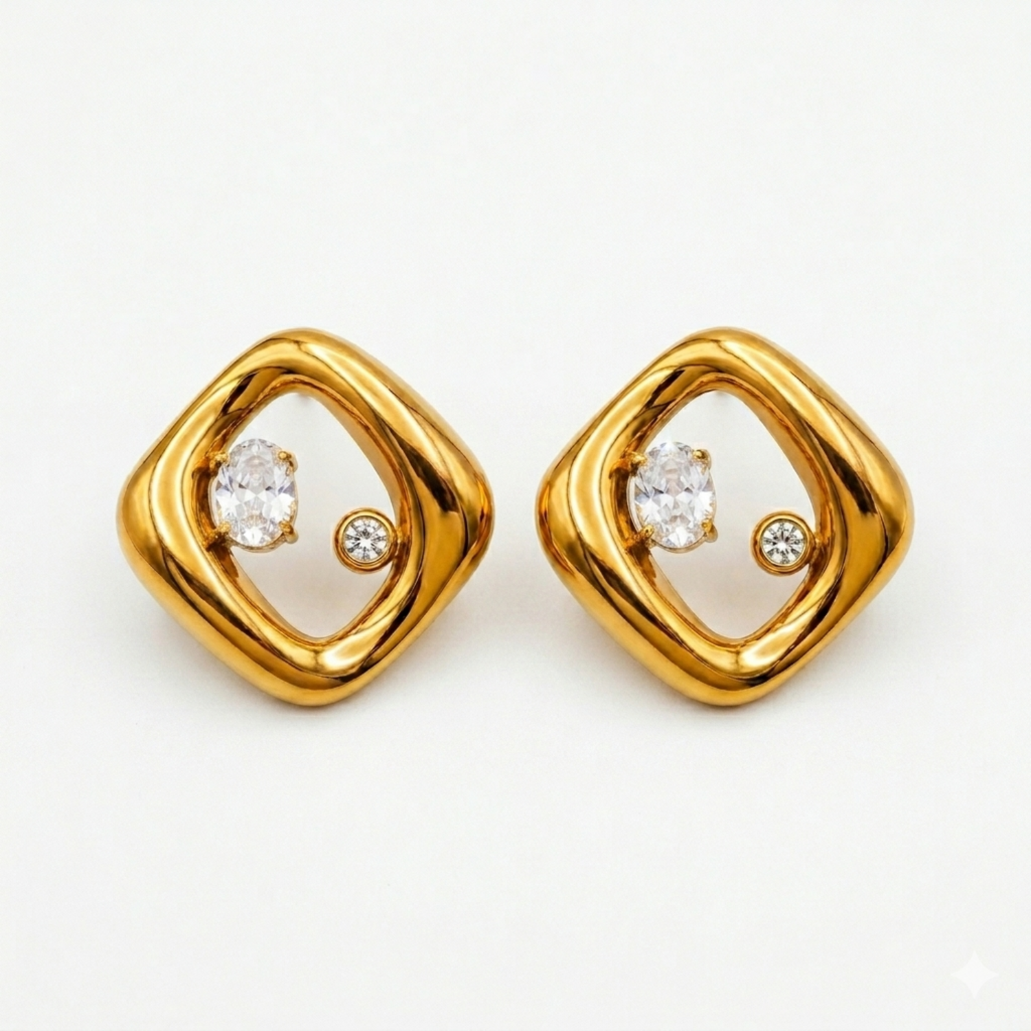 A pair of gold-plated abstract rhombus-shaped stud earrings for women featuring two floating crystals inside a molten gold frame, shown on a white background.