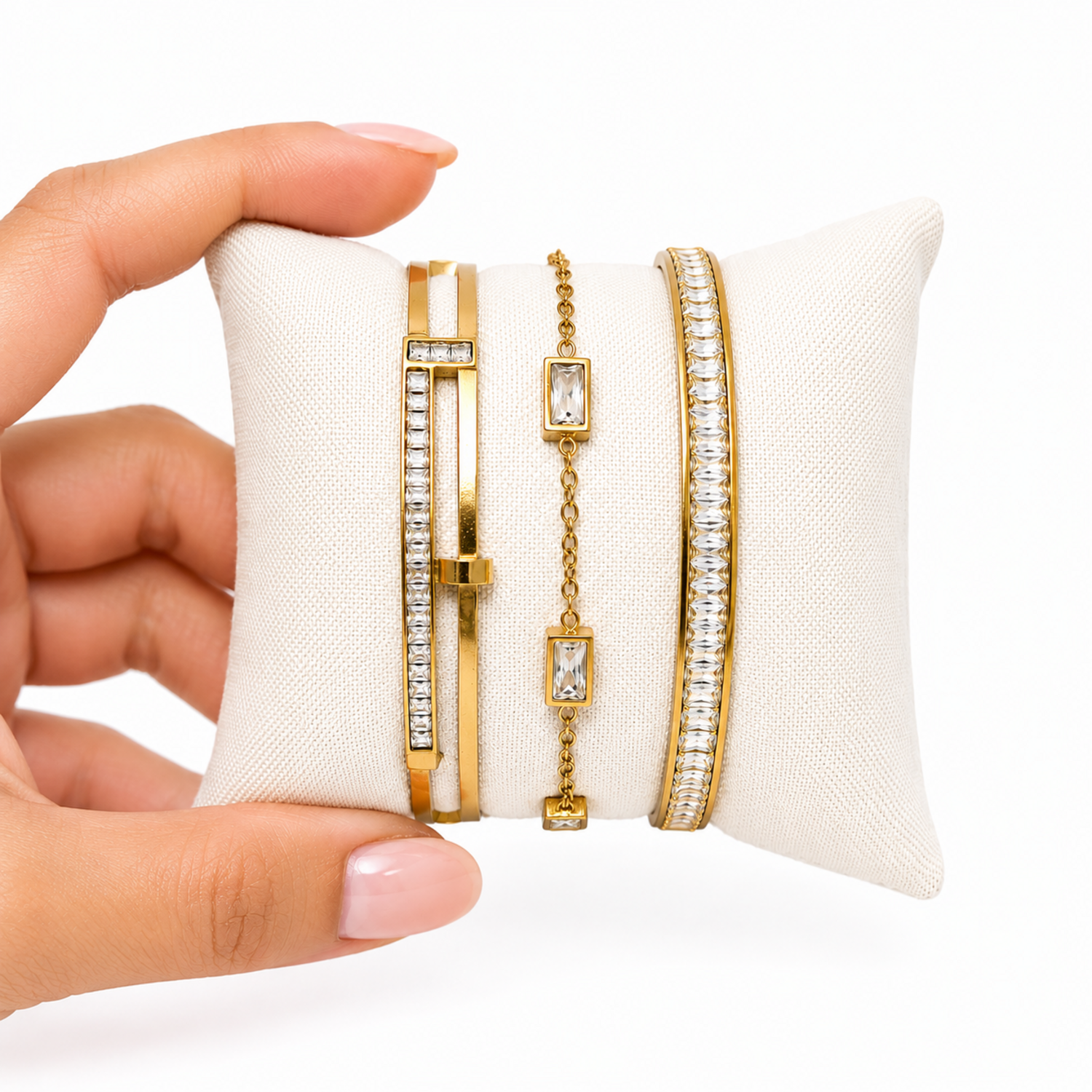A close-view of a premium three-piece gold-plated bracelet stack for women featuring two geometric crystal station bangles and a central multi-cut crystal statement chain bracelet.