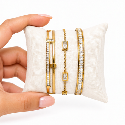 A close-view of a premium three-piece gold-plated bracelet stack for women featuring two geometric crystal station bangles and a central multi-cut crystal statement chain bracelet.