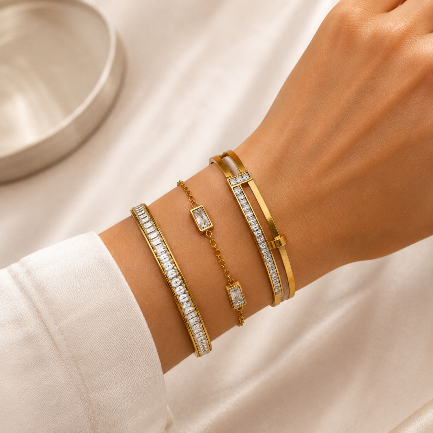 A premium three-piece gold-plated bracelet stack for women featuring two geometric crystal station bangles and a central multi-cut crystal statement chain bracelet, on a model