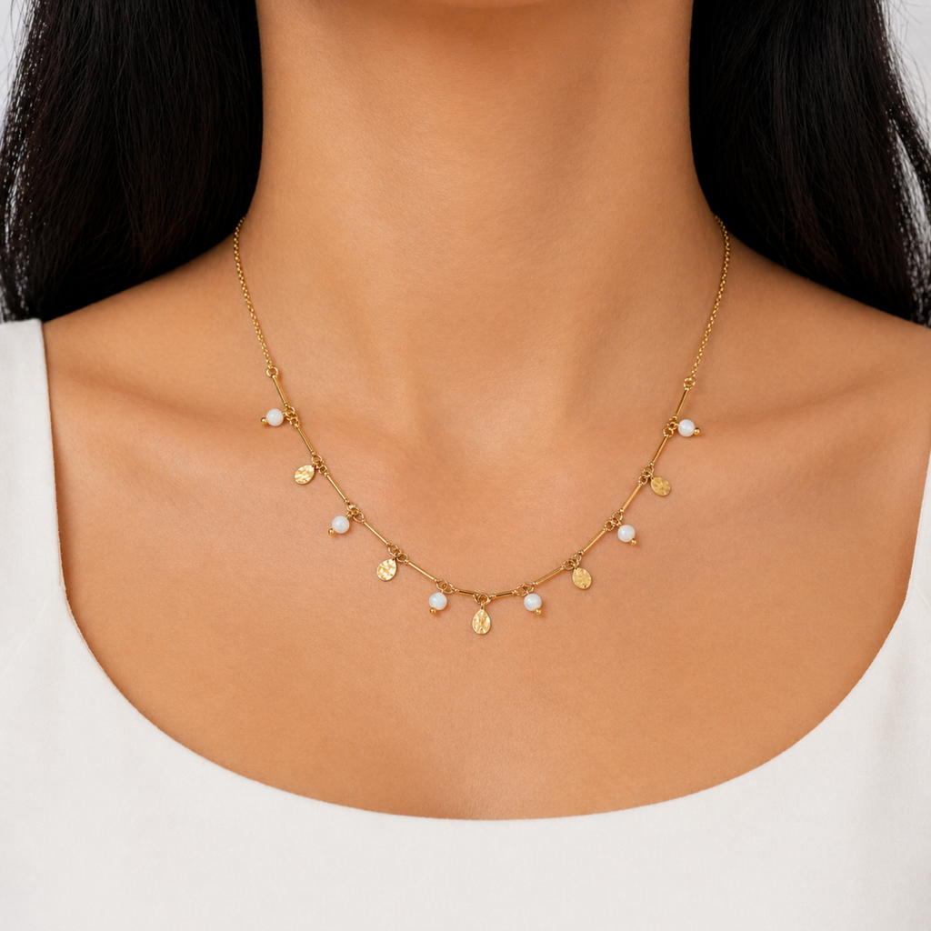 A gold-plated stainless steel chain for women featuring a bar-link design with dangling milky opals and hammered gold charms, shown on a model