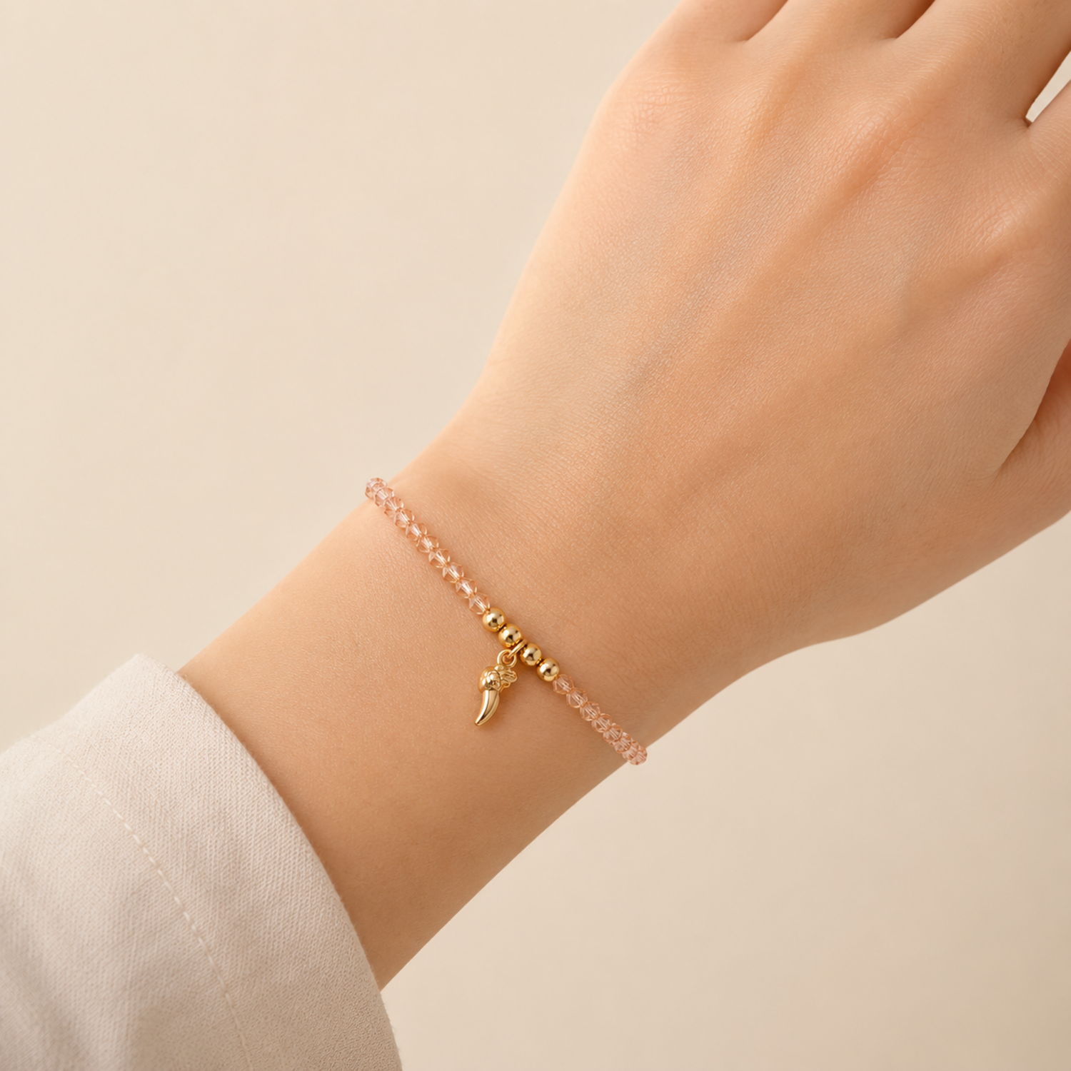 A rose-toned crystal chain bracelet for women featuring a gold talon charm and polished golden beads, shown on a model