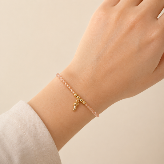 A rose-toned crystal chain bracelet for women featuring a gold talon charm and polished golden beads, shown on a model
