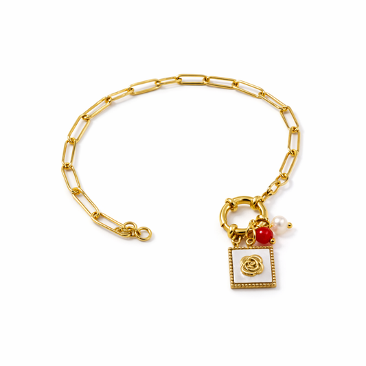 A gold-plated paperclip chain bracelet for women featuring a toggle clasp with rose, red bead, and pearl charms, shown on a white background