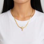 A gold-plated stainless steel chain for women featuring a flat high-shine texture and an open clover pendant with a small gold drop shown on a model