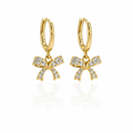 A pair of gold-plated hoop earrings for women featuring a sparkling crystal-encrusted bow drop, shown on a white background