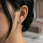 A gold-plated hoop earrings for women featuring a sparkling crystal-encrusted bow drop, shown on a model