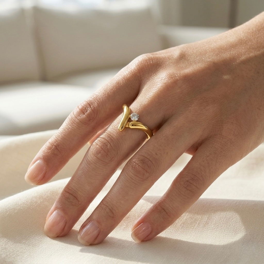 Gold plated ring with a white stone at the centre on a model hand